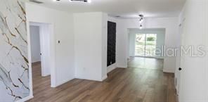 An interior view showing a living area with wood-look flooring and a marble-patterned accent wall — 1152 NE 9 STREET, OCALA, FL