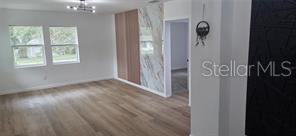A living room with light wood flooring, a marble accent wall, and a black feature wall — 1152 NE 9 STREET, OCALA, FL