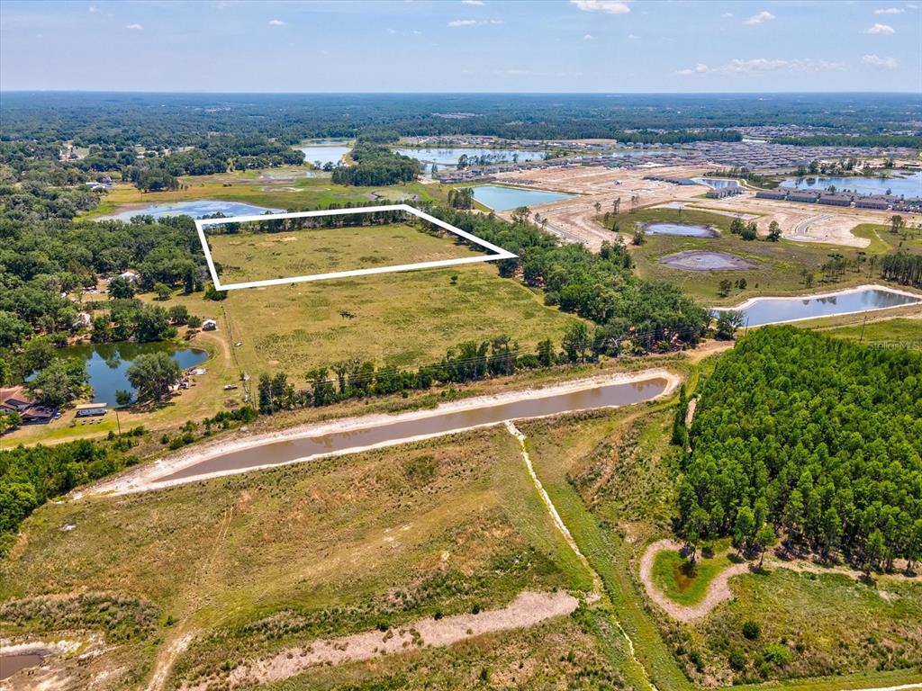 An aerial view shows a large, rectangular plot of land outlined in white near water — 8989 EHREN CUTOFF, LAND O LAKES, FL
