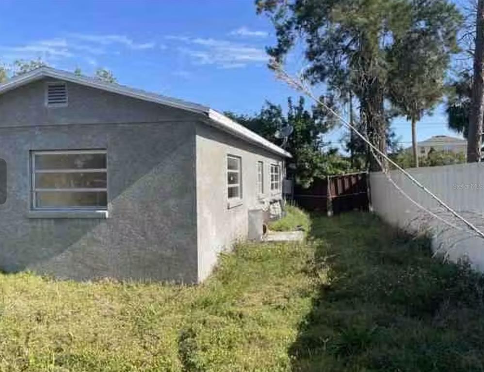 The exterior of a single-story house with stucco walls, two windows, and a white door — 806 W SHELL POINT ROAD, RUSKIN, FL
