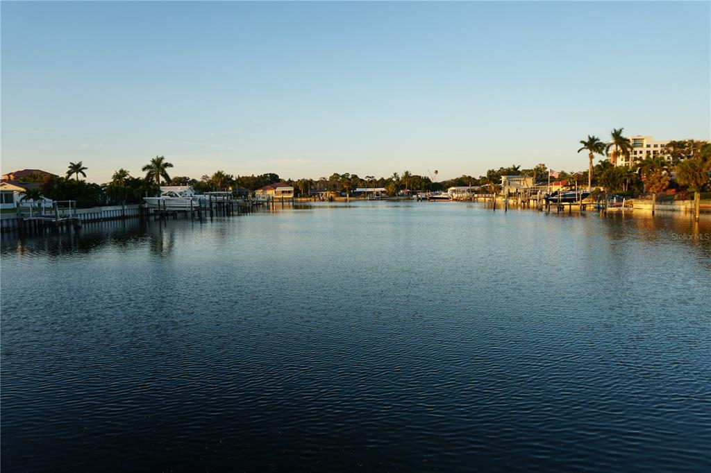 A wide canal view features residential docks, boats, and palm trees under a clear sky — 3753 46TH AVENUE S UNIT 12, ST PETERSBURG, FL
