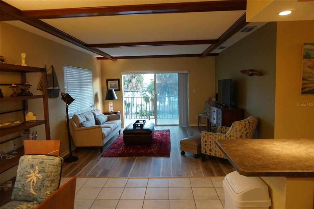 A living room features wood-look flooring, a sliding glass door to a balcony, and beams — 3753 46TH AVENUE S UNIT 12, ST PETERSBURG, FL