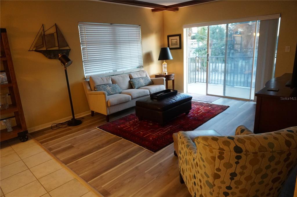 A living room features a sofa, leather ottoman, patterned armchair, and a sliding glass door — 3753 46TH AVENUE S UNIT 12, ST PETERSBURG, FL