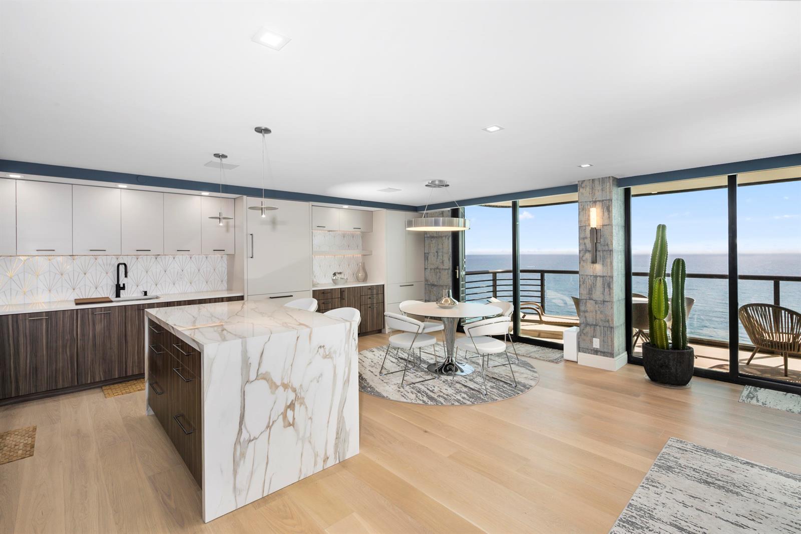 A modern kitchen and dining area feature a marble island, wood cabinetry, and ocean views — 250 S Ocean Boulevard # F, Boca Raton FL 33432, BOCA RATON, FL