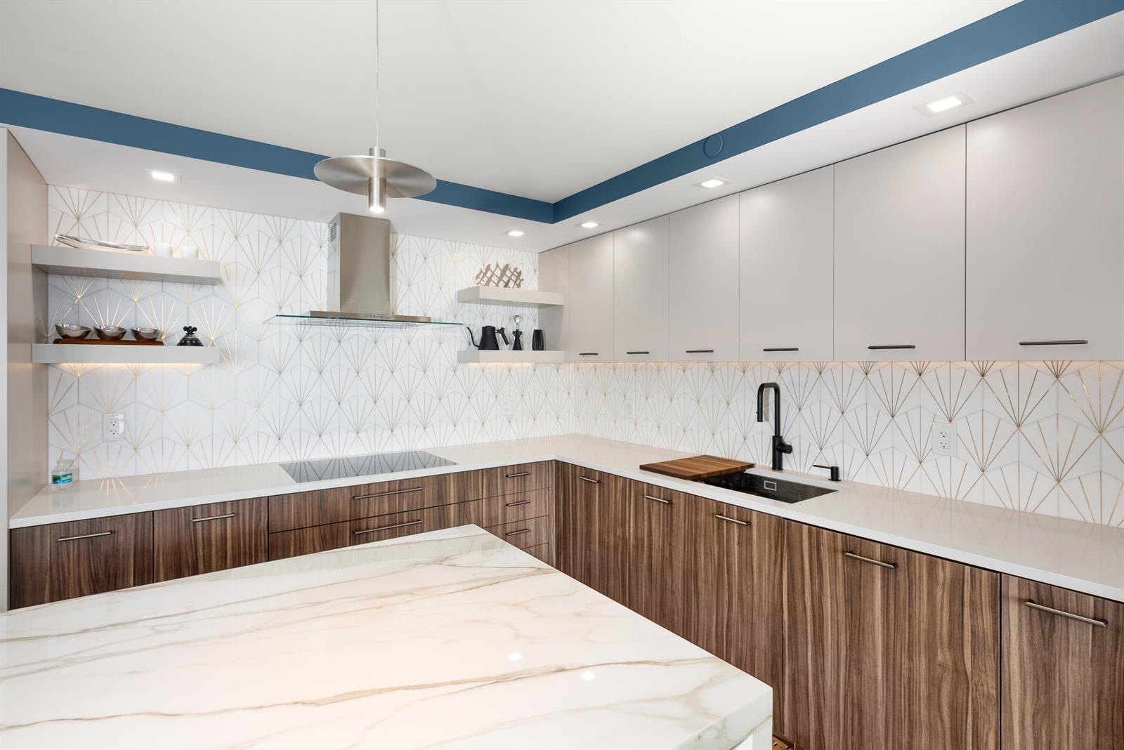A modern kitchen features wood-grain lower cabinets, white upper cabinets, and a geometric-patterned tile backsplash — 250 S Ocean Boulevard # F, Boca Raton FL 33432, BOCA RATON, FL