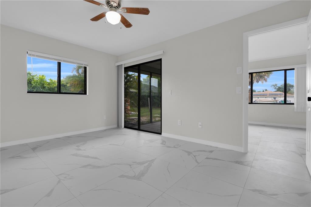 A room with white marble-look tile flooring, a ceiling fan, and sliding glass patio doors — 6359 HERA STREET UNIT B, ENGLEWOOD, FL