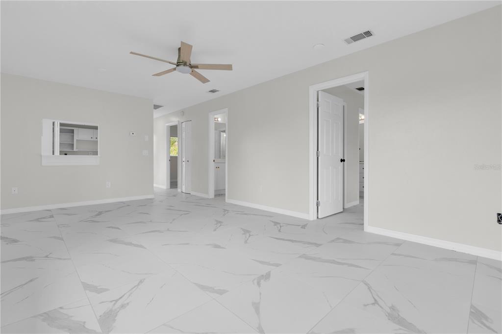 An empty room with white walls, large marble-patterned floor tiles, and a ceiling fan — 6359 HERA STREET UNIT B, ENGLEWOOD, FL