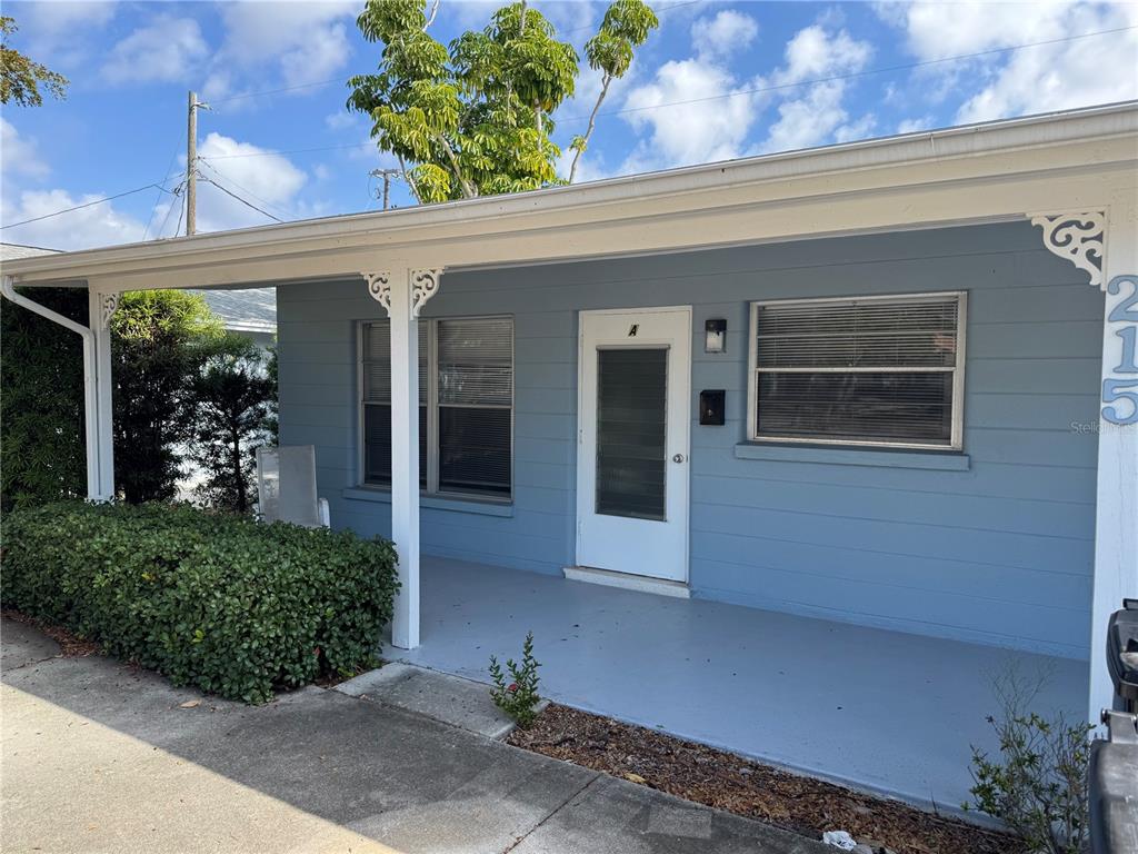 A light blue house exterior features a covered porch, a white door, and two windows — 215 PARK BOULEVARD S UNIT A, VENICE, FL