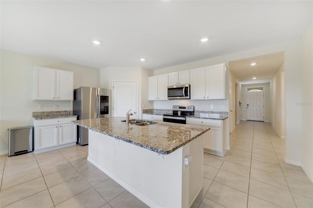 A kitchen features white cabinets, granite countertops, stainless steel appliances, and a central island — 2135 E OLD MILL DRIVE, DELTONA, FL