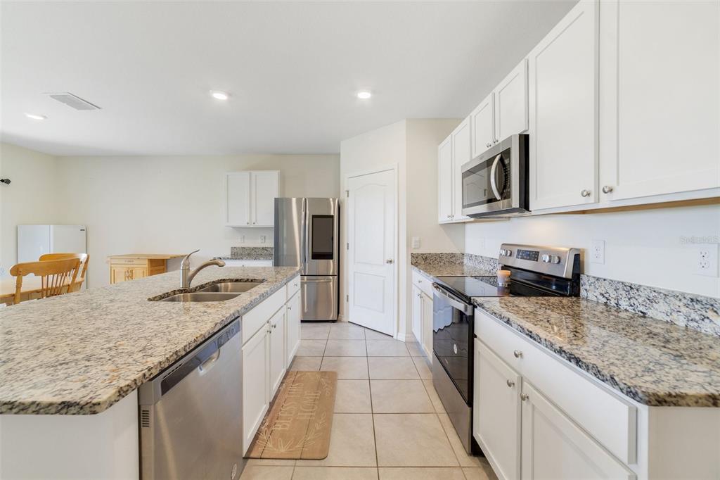 A kitchen with white cabinets, granite countertops, stainless steel appliances, and tile flooring — 2135 E OLD MILL DRIVE, DELTONA, FL