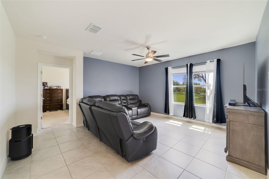 A living room features light tile flooring, a blue accent wall, and a black sofa — 2135 E OLD MILL DRIVE, DELTONA, FL
