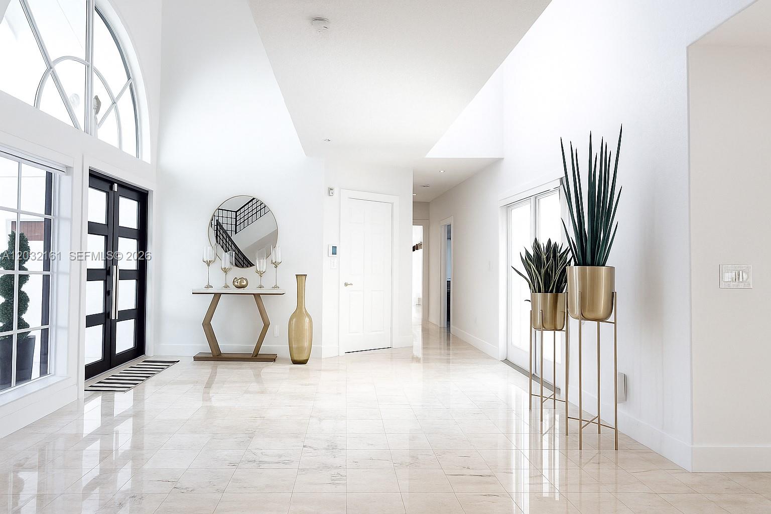 A bright, modern entryway features white walls, marble tile floors, and gold-toned decorative accents — 15106 NW 89th Ct, Miami Lakes FL 33018, MIAMI LAKES, FL