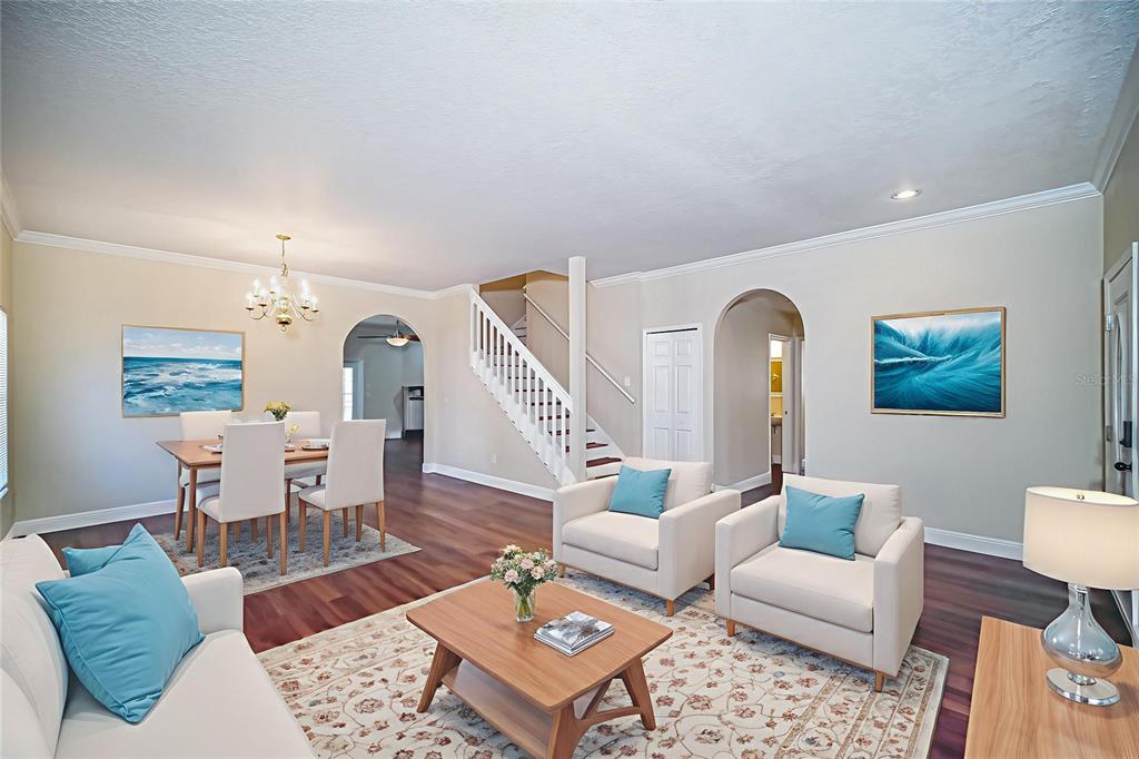 A living and dining area features white furniture, wood floors, a staircase, and arched doorways — 2509 SKIF DRIVE, ORLANDO, FL