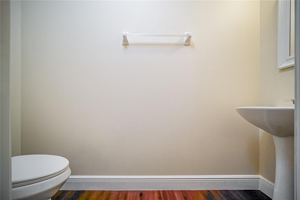 A small bathroom features a pedestal sink, a toilet, and a towel bar on beige walls — 2509 SKIF DRIVE, ORLANDO, FL