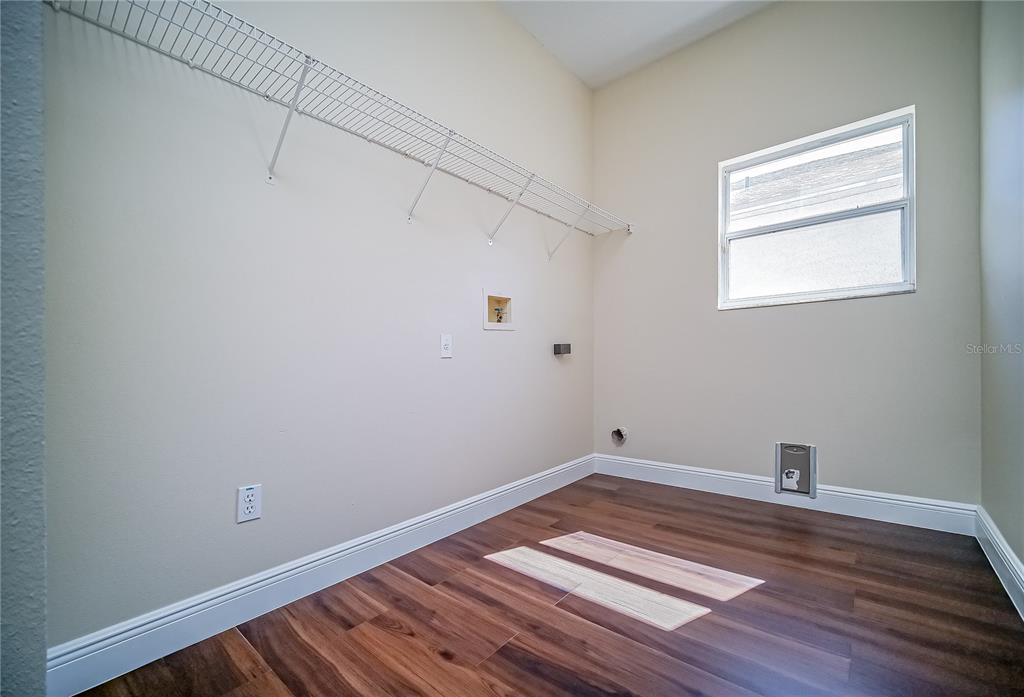 A laundry room features wood-look flooring, a wire shelf, and hookups for appliances — 2509 SKIF DRIVE, ORLANDO, FL