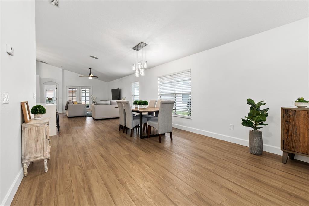 An open-concept dining and living area features wood-look flooring, white walls, and a modern chandelier — 14018 BUDWORTH CIRCLE, ORLANDO, FL