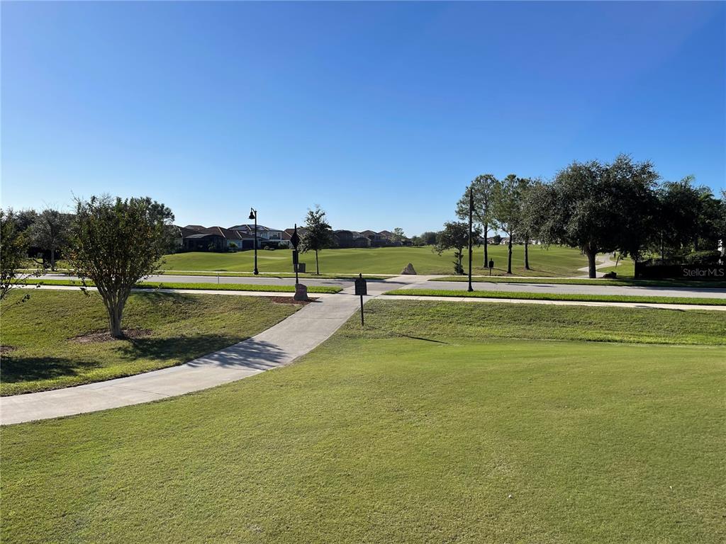 A paved walkway leads through a grassy residential area toward a golf course and houses — 14018 BUDWORTH CIRCLE, ORLANDO, FL