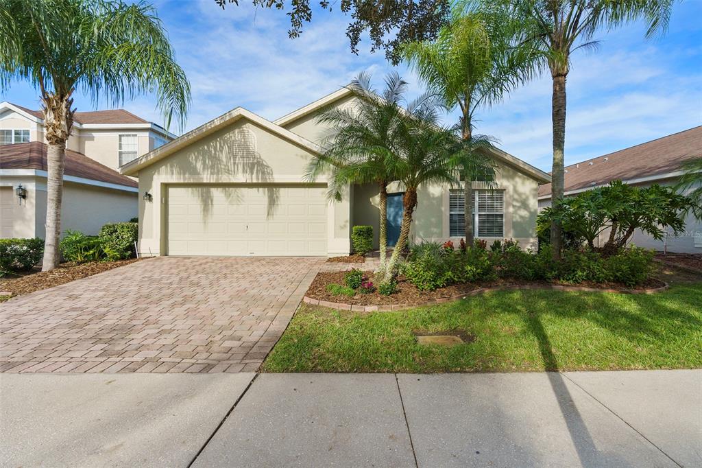 A single-story house with a paved driveway, a two-car garage, and palm trees in front — 14018 BUDWORTH CIRCLE, ORLANDO, FL