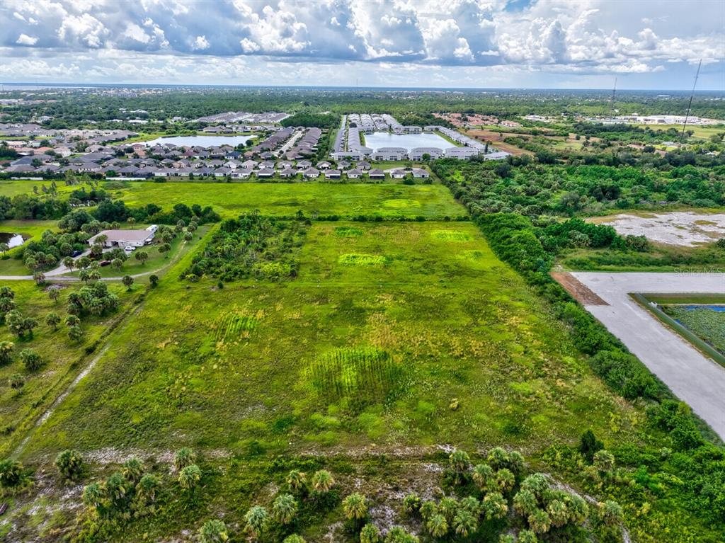 An aerial view shows a large, undeveloped grassy lot surrounded by trees and residential neighborhoods — 3000 ROWLAND DRIVE UNIT Tract C, PUNTA GORDA, FL