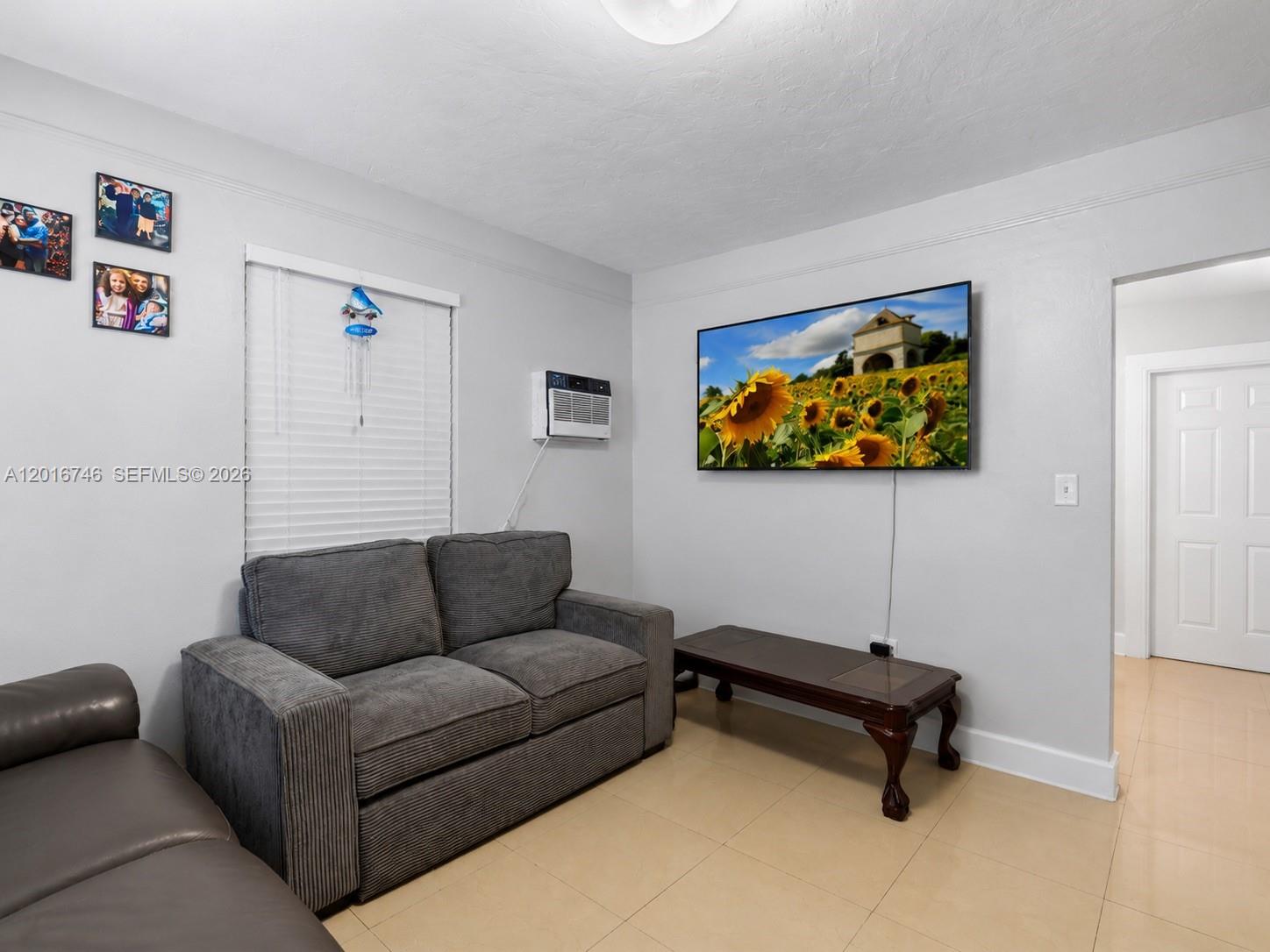 A living room features a gray sofa, a coffee table, and a wall-mounted television — 1111 NW 77th St, Miami FL 33150, MIAMI, FL