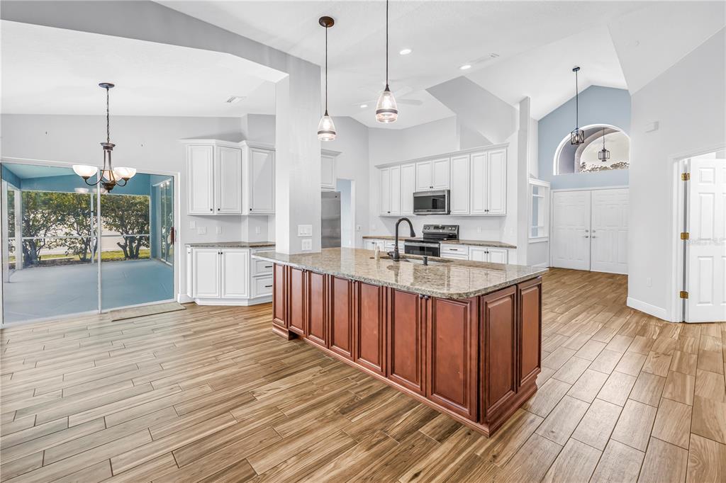 A kitchen with white cabinets, a dark wood island, and wood-look tile flooring — 18812 BASCOMB LANE, HUDSON, FL