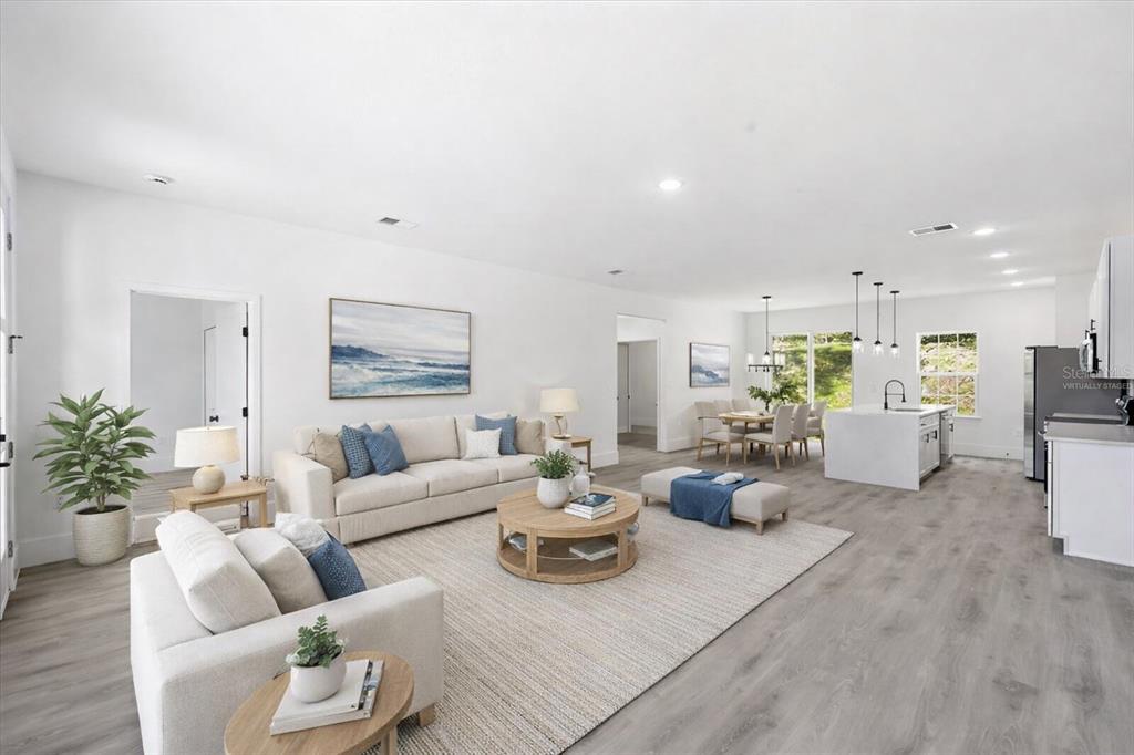 This is a virtually staged open-concept living room, dining area, and kitchen with light flooring — 2670 W FAIRWAY LOOP, CITRUS SPRINGS, FL