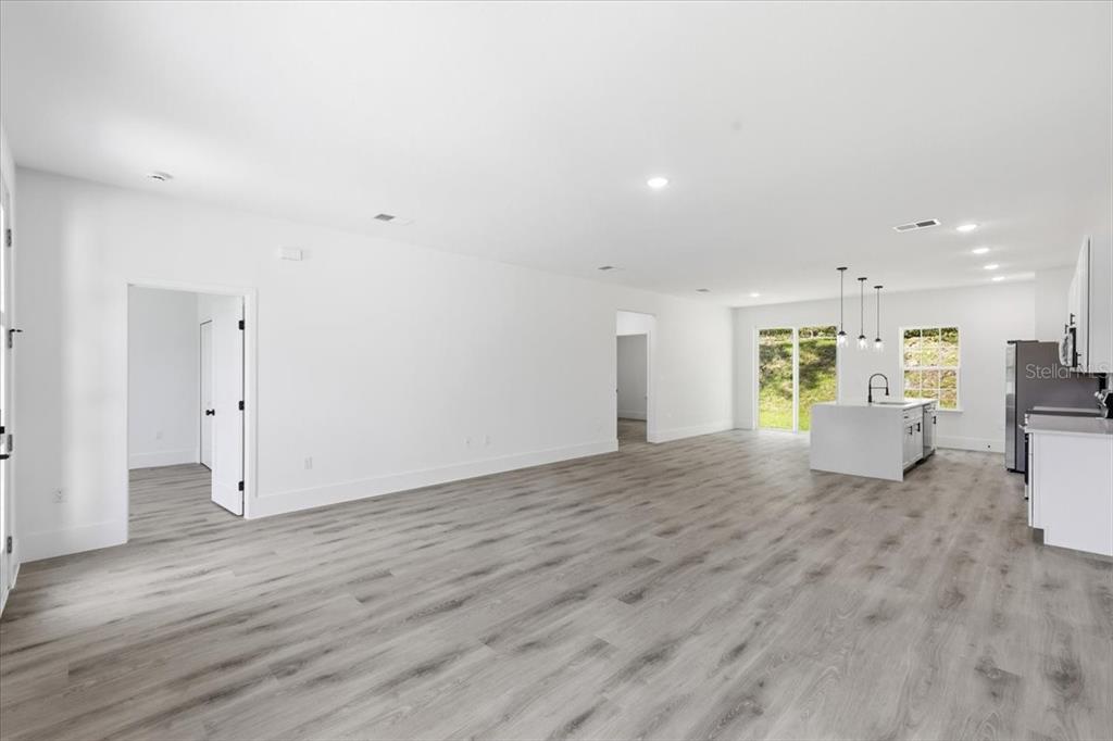 An open-concept living area features light wood-look flooring, white walls, and a modern kitchen island — 2670 W FAIRWAY LOOP, CITRUS SPRINGS, FL