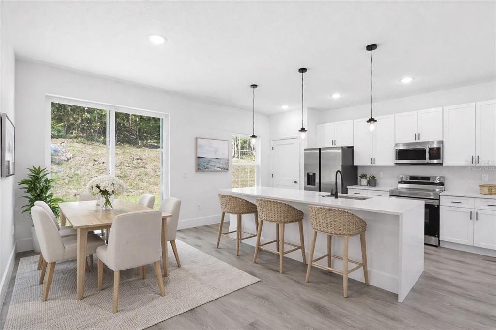 A bright kitchen and dining area features white cabinetry, a large island, and wood flooring — 2670 W FAIRWAY LOOP, CITRUS SPRINGS, FL
