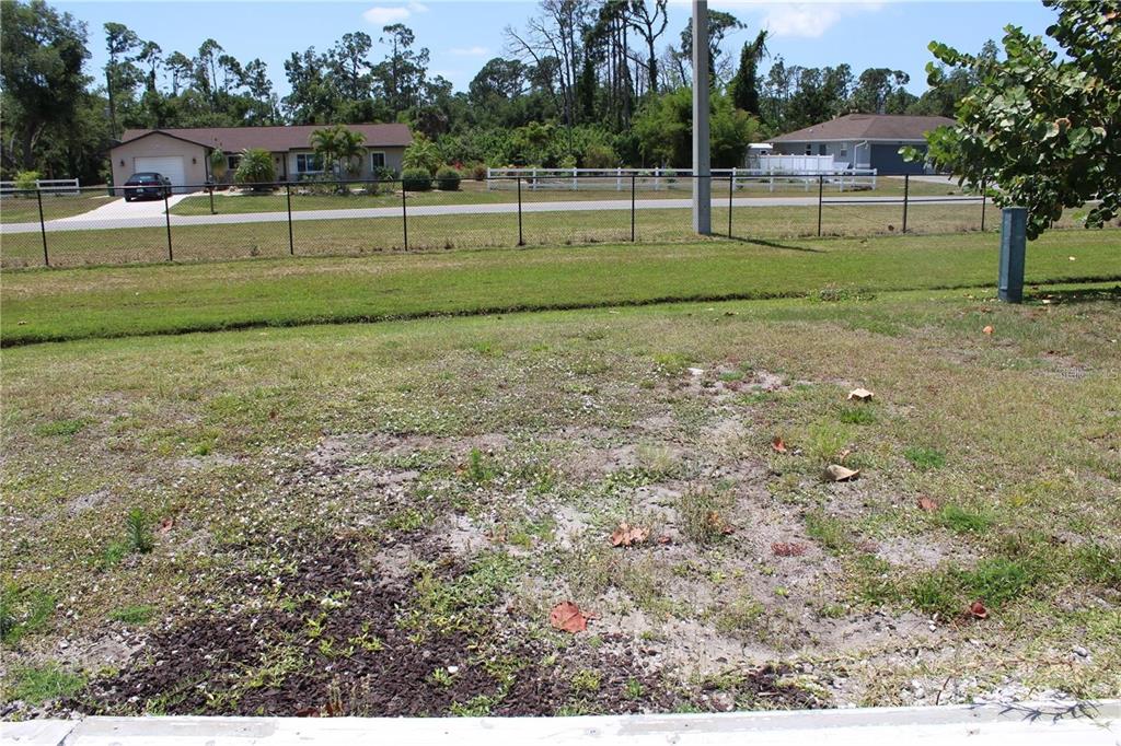 A view of a grassy, partially bare lot looking toward a house across the street — 5150 PALENA BOULEVARD UNIT 294, NORTH PORT, FL