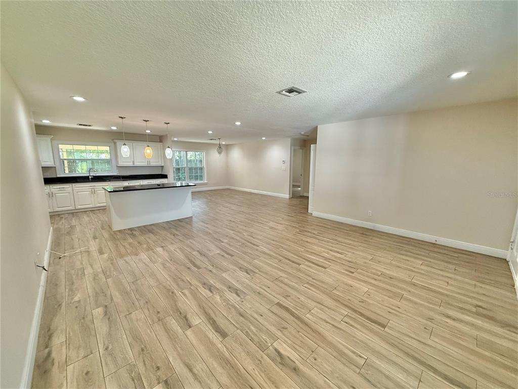 An open-concept kitchen and living area feature light wood-look tile flooring and white cabinetry — 2810 FLOWERTREE ROAD, BELLE ISLE, FL