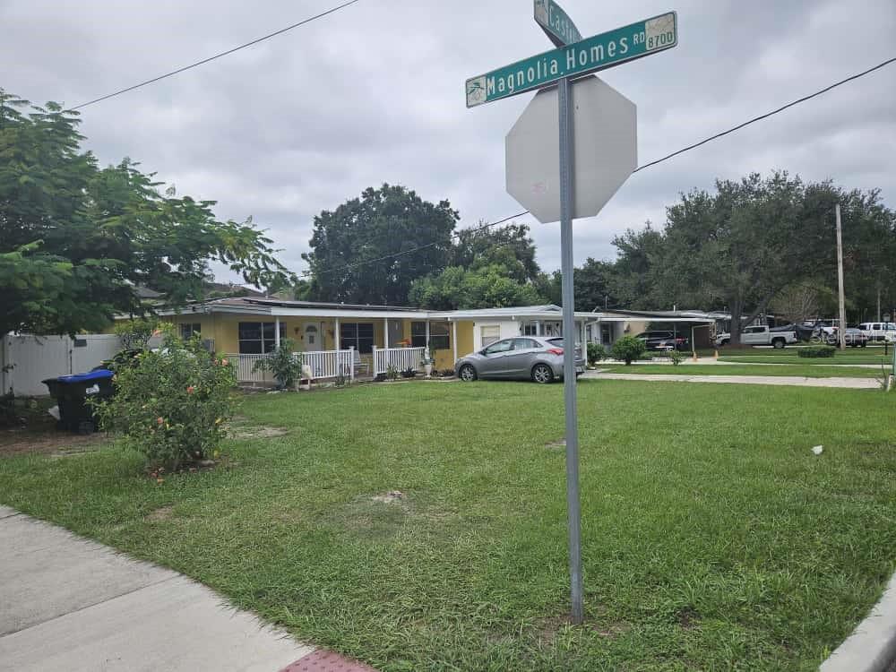 A yellow single-story house sits behind a street sign at a corner intersection — 3902 CASTELL DRIVE, ORLANDO, FL