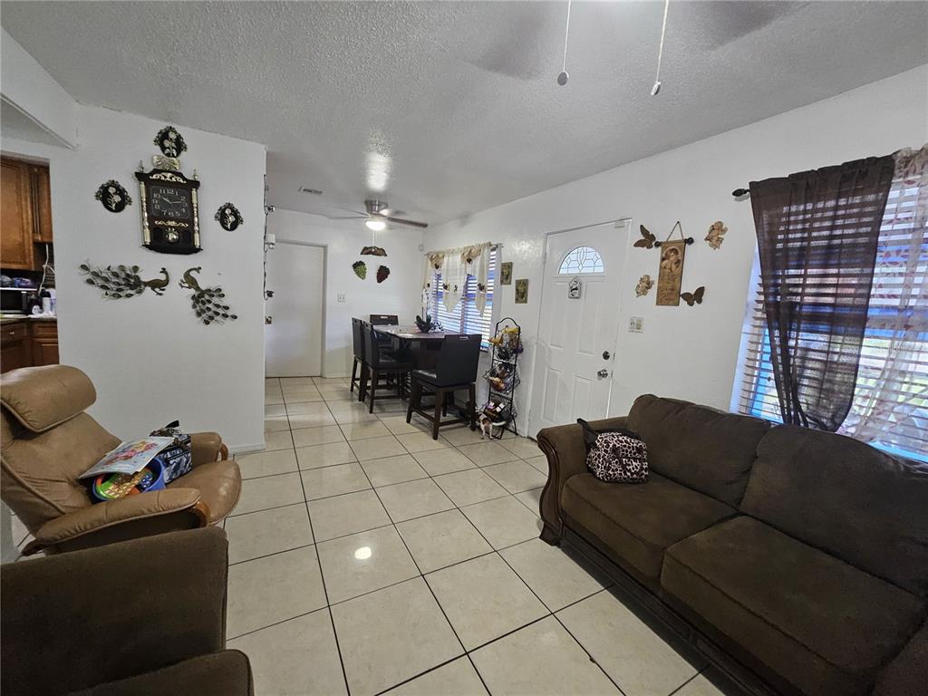 A living room and dining area with tile flooring, white walls, and brown furniture — 3902 CASTELL DRIVE, ORLANDO, FL