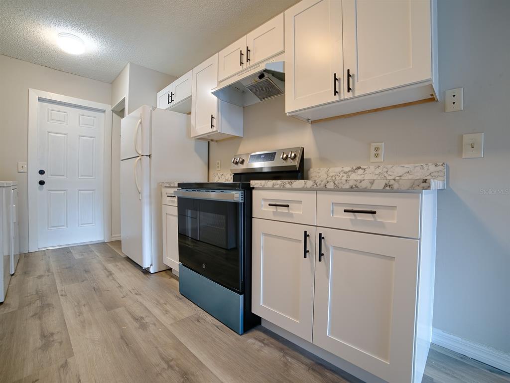A kitchen with white cabinets, stainless steel appliances, and marble-look countertops — 488 W ROSEWOOD LANE UNIT 488, TAVARES, FL