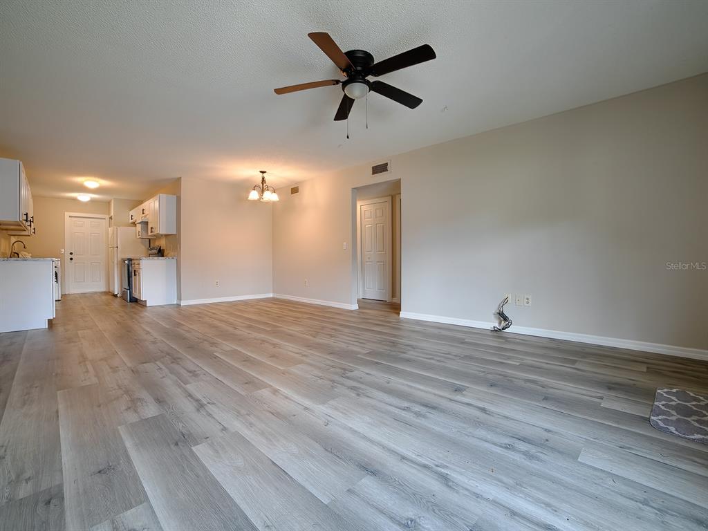 An open-concept living and dining area features light wood-look flooring and a ceiling fan — 488 W ROSEWOOD LANE UNIT 488, TAVARES, FL