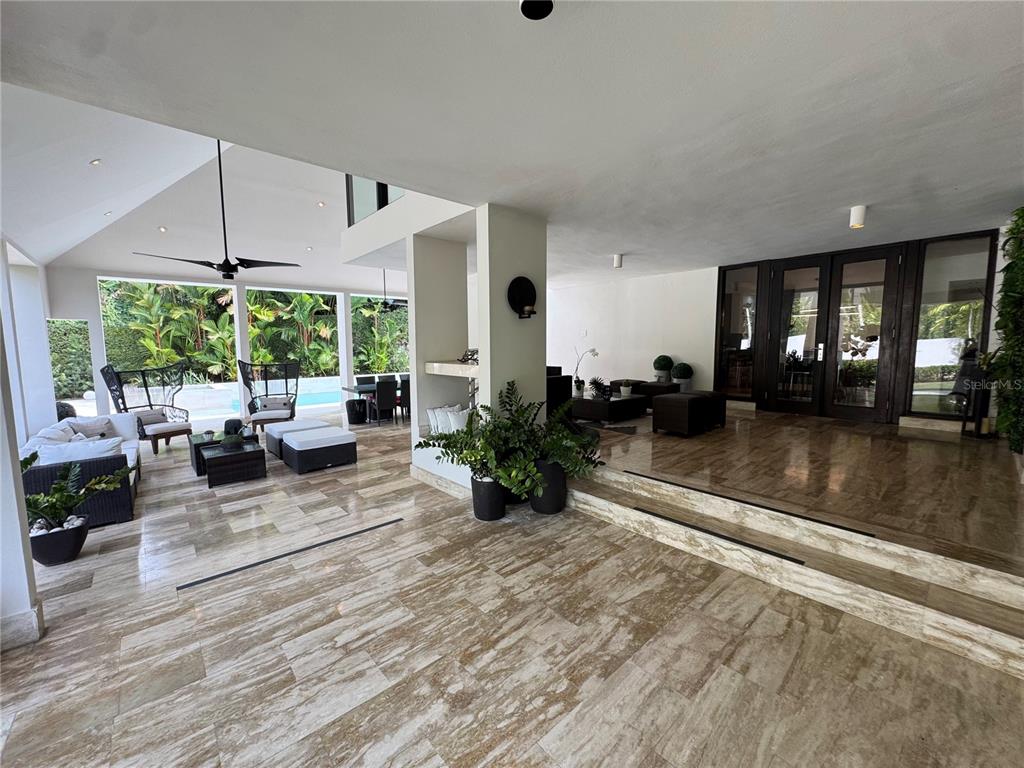A spacious covered patio features marble flooring, outdoor seating, and a view of a pool — #9 Palma Real ESTANCIAS DE TORRIMAR, GUAYNABO, PR