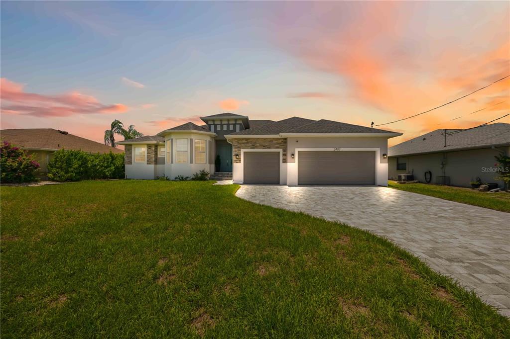 A single-story house with a stone-accented facade, a three-car garage, and a paved driveway — 2483 HERRON TERRACE, PORT CHARLOTTE, FL