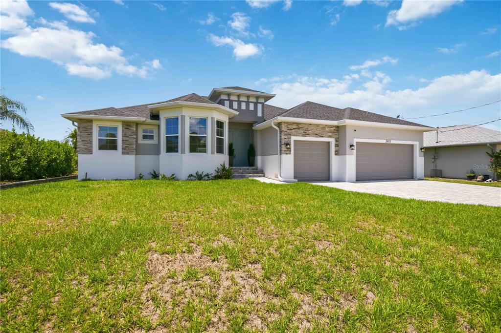 A single-story house with a stone-accented facade, a three-car garage, and a large front lawn — 2483 HERRON TERRACE, PORT CHARLOTTE, FL