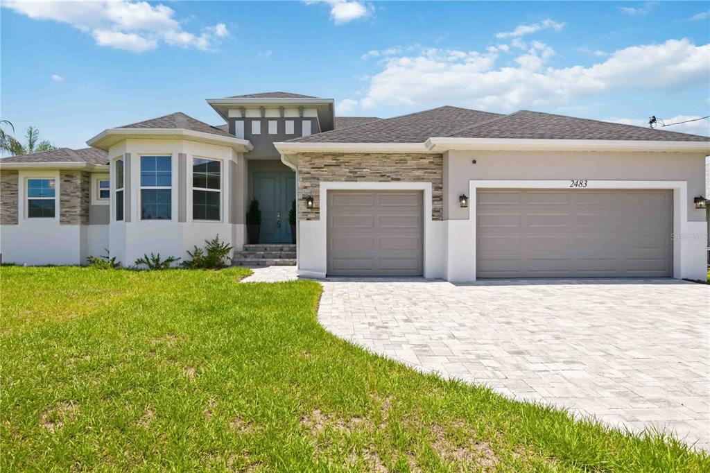 A single-story house features a stone-accented facade, a three-car garage, and a paved driveway — 2483 HERRON TERRACE, PORT CHARLOTTE, FL