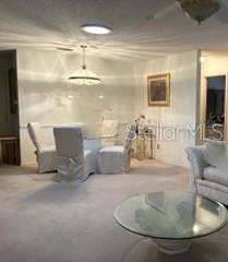 A dining area with a glass table and chairs sits adjacent to a carpeted living room — 8519 SW 91ST STREET UNIT B, OCALA, FL