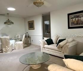A living room and dining area with carpeted floors, a glass coffee table, and white furniture — 8519 SW 91ST STREET UNIT B, OCALA, FL