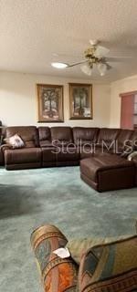 A living room features a large brown leather sectional sofa, teal carpeting, and two framed pictures — 8519 SW 91ST STREET UNIT B, OCALA, FL