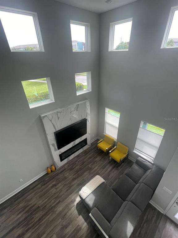 A living room features a fireplace, a grey sectional, two yellow chairs, and high ceilings — 5898 BIMINI TWIST LOOP, ORLANDO, FL