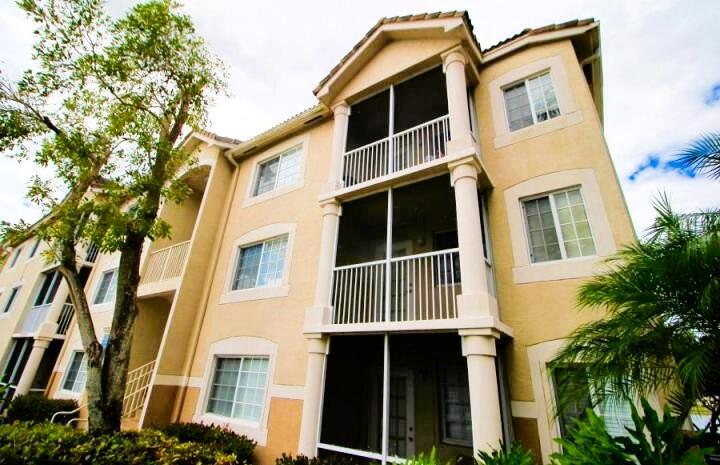 A three-story apartment building with beige stucco walls and screened-in balconies — 8935 Okeechobee Boulevard # 204, West Palm Beach FL 33411, WEST PALM BEACH, FL