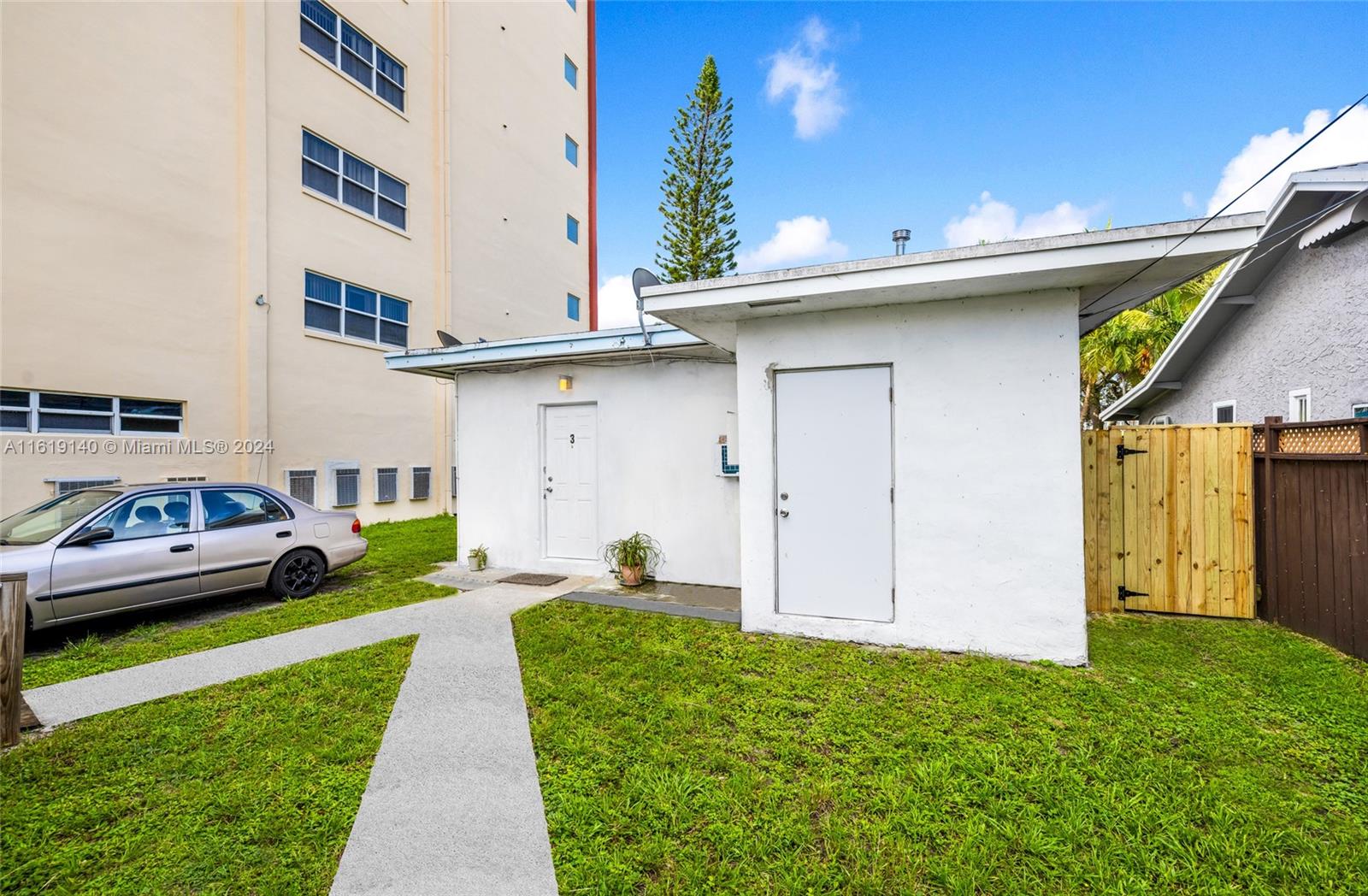 A small white detached building with two doors sits on a lawn beside a car — 1711 Buchanan St, Hollywood FL 33020, HOLLYWOOD, FL