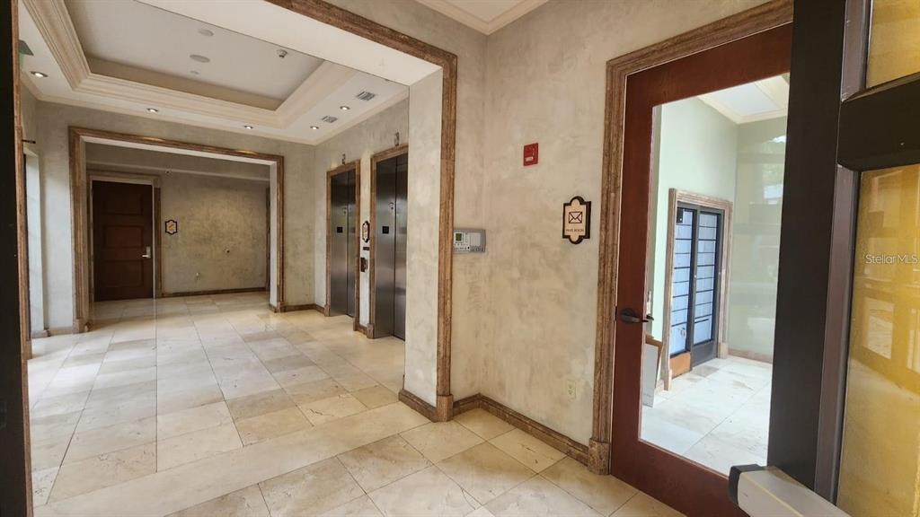 A lobby area features tile flooring, two elevators, and a glass-paneled door leading to another room — 7065 WESTPOINTE BOULEVARD UNIT 305, ORLANDO, FL