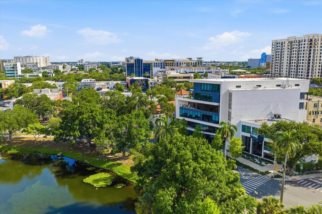 An aerial view shows a modern white and glass office building beside a small lake — 132 MIRROR LAKE UNIT 403, ST PETERSBURG, FL