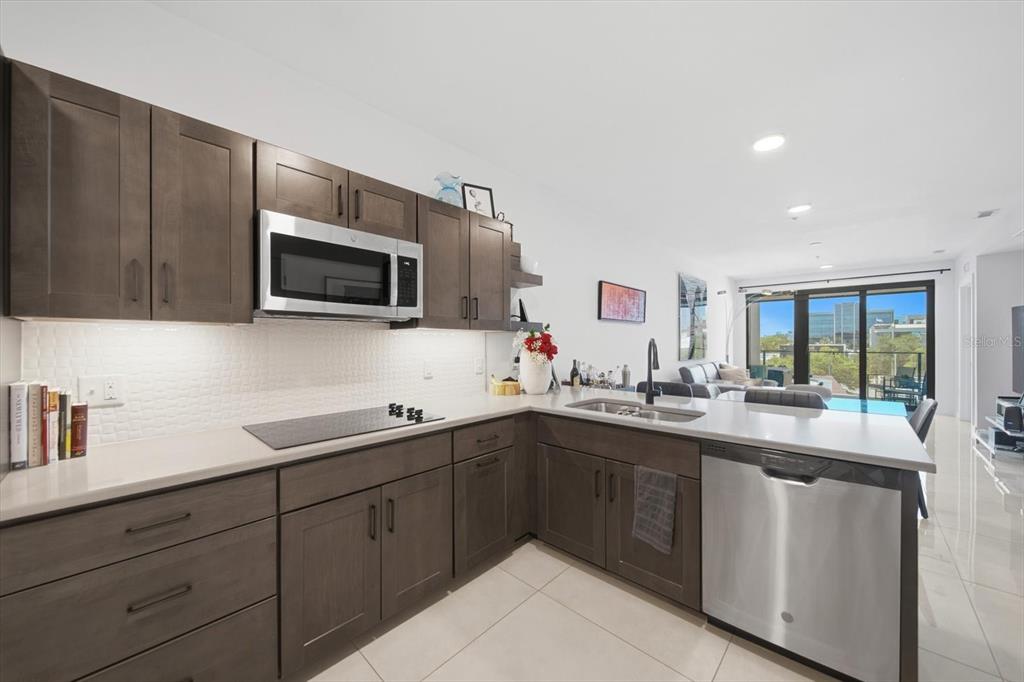 A modern kitchen features dark wood cabinets, stainless steel appliances, and a light-colored countertop — 132 MIRROR LAKE UNIT 403, ST PETERSBURG, FL