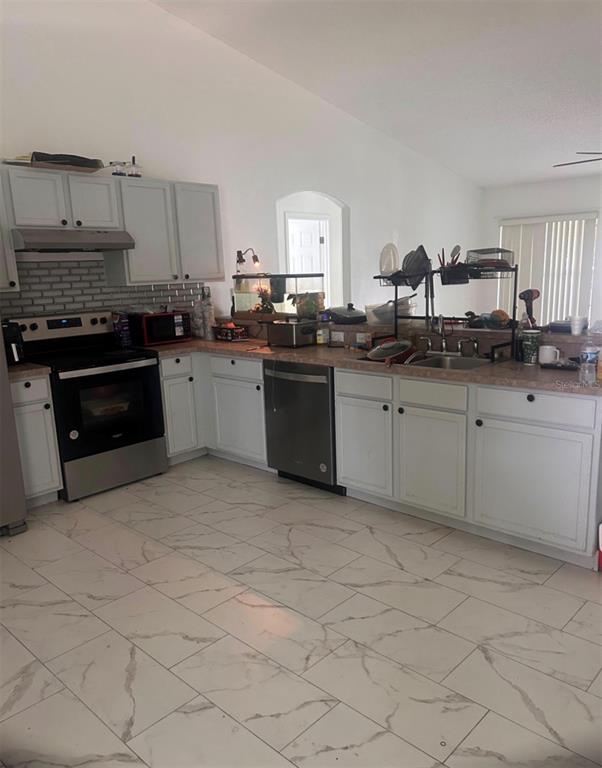 A kitchen features light-colored cabinets, stainless steel appliances, and white marble-patterned tile flooring — 33 COVENTRY COURT, KISSIMMEE, FL