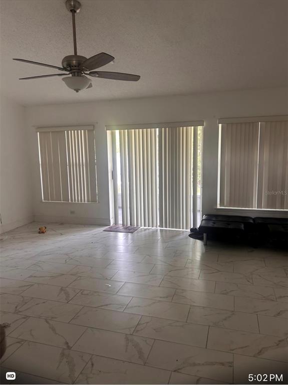 A living room features white marble-look tile flooring, a ceiling fan, and vertical window blinds — 33 COVENTRY COURT, KISSIMMEE, FL