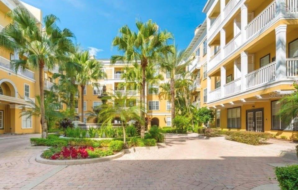 A courtyard with a fountain, palm trees, and yellow multi-story apartment buildings — 860 N ORANGE AVENUE UNIT 146, ORLANDO, FL
